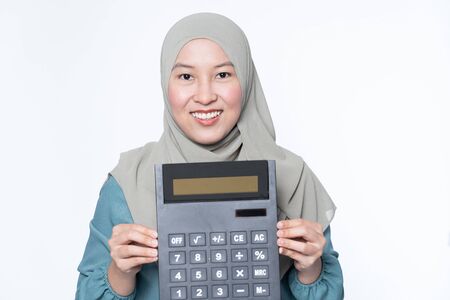 Female muslim holding a big calculator with facial expression - financial concept.の写真素材