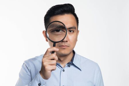 Asian man looking into a magnifying glass.の写真素材