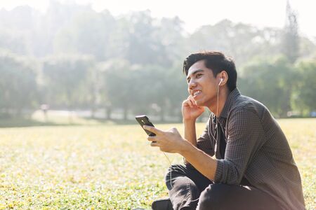 Young man selecting and listen to music using his deviceの写真素材