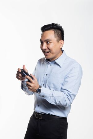 Asian man in work cloth playing console gameの写真素材