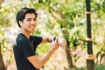 Young man touching his digital fitness tracker in a parkの写真素材