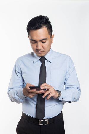Asian man in office wear using his phoneの写真素材