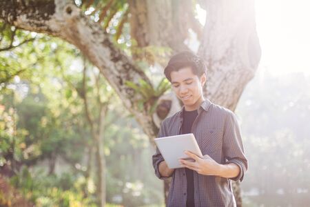 Young man using tablet device in a parkの写真素材