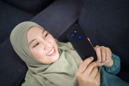 Beautiful muslim woman using her mobile device with facial expression.の写真素材
