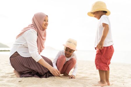 Asian kids having leisure time with their mother at the beach.の写真素材