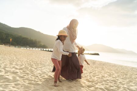 Asian kids having leisure time with their mother at the beach.の写真素材