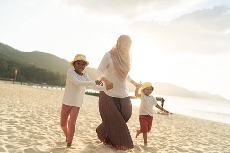 Asian kids having leisure time with their mother at the beach.の写真素材
