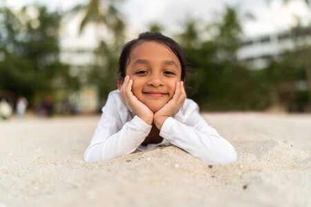 Girl lying down smiling on a beach sand.の写真素材