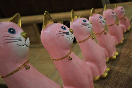 pink cat figurines in a row on a wooden background.の写真素材