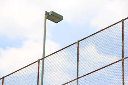 Metal fence with a street lamp on a background of blue sky.の写真素材