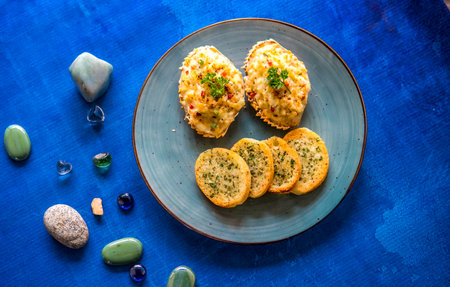Crispy bread with cheese and herbs on a blue plate top viewの写真素材