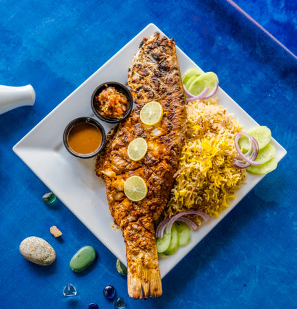 Whole fish served alongside yellow rice with lime garnish and accompanying saucesの写真素材