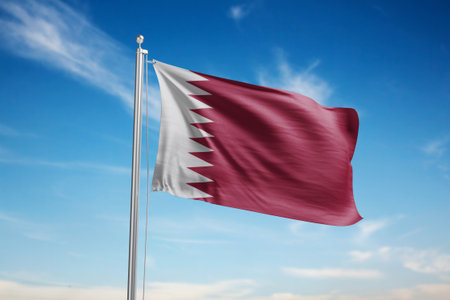 Qatar flag waving in the wind against blue sky with white cloudsの写真素材