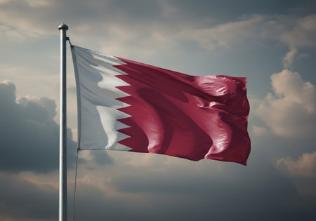 Qatar flag waving in the wind against a blue sky with cloudsの写真素材
