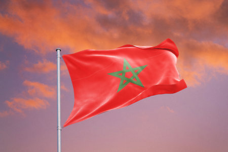 Morocco flag waving in the wind against blue sky with clouds