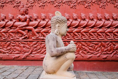 Stone carving statue with a carving on the wall behind.の写真素材