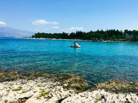 Brac Island Croatia in the middle of summer. With boats and people enjoying summer in the sandy bay.のeditorial素材