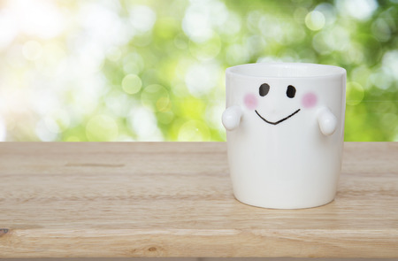happy smiley face cup on wood tableの写真素材