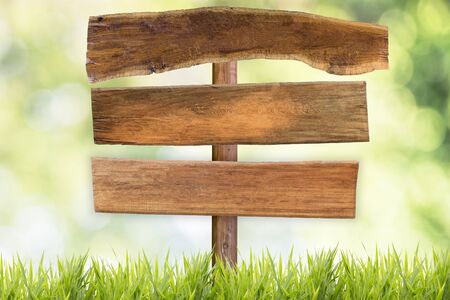wooden signboard with grass field and green blurred backgroundの写真素材