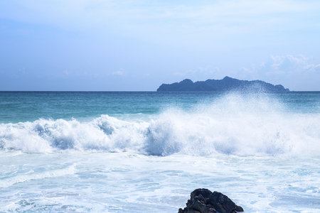 Splashing waves on the rocks and blue skyの写真素材