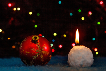 Christmas-tree decoration and snowball-candle against multicolored defocused lightsの写真素材