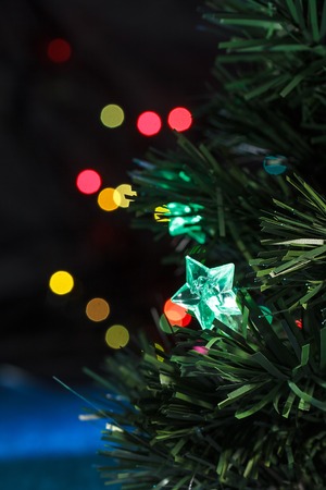 Christmas tree with garland against multicolored defocused lightsの写真素材