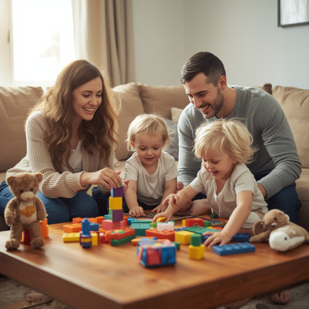 Beautiful young family is playing with children and smiling while sitting on sofa at homeの素材