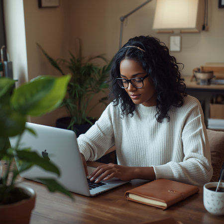 Attractive african american woman in eyeglasses using laptop while sitting in cafeの素材