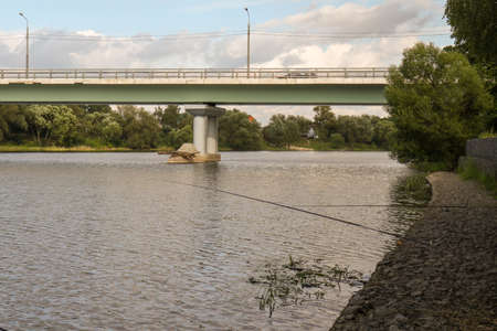 Fishing on a feeder at sunset near the bridge.の写真素材