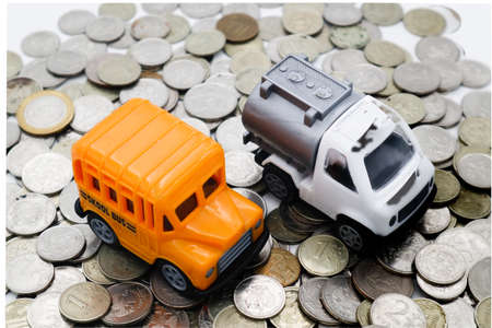 Toy school bus and a special vehicle for transporting gas on a slide made of metal coins.の写真素材