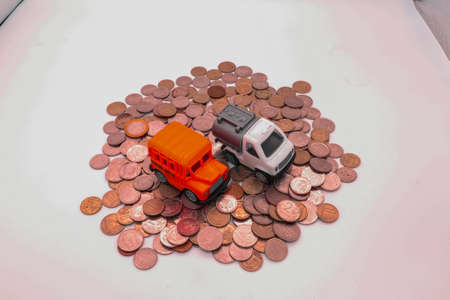 Toy school bus and a special car for transporting gas on a slide made of metallic money. Sphere viewの写真素材