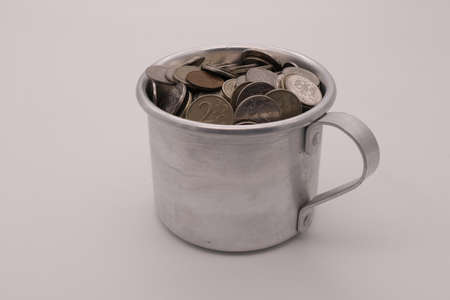 Cup with coins for tips isolated on white backgroundの写真素材