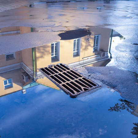 Reflection of blue skies and houses in a puddle after rainの写真素材