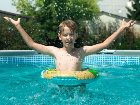 A 9-year-old boy plays in the frame pool at the cottage. Games in the poolの写真素材