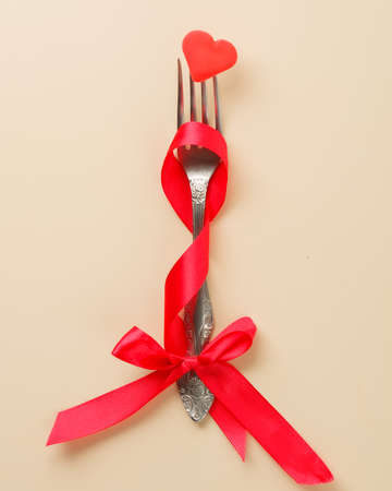 Conceptual stock photo, valentine's day greeting card. A fork with a ribbon and a pierced heart....