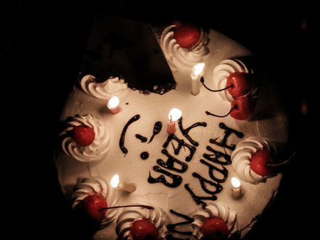Happy New Year cake missing a piece  with a candleの写真素材