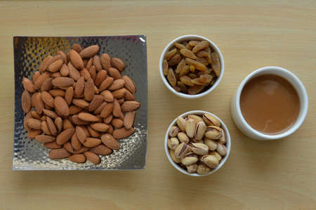 Roasted almond with sweet raisins and pistachios isolated on the wooden table