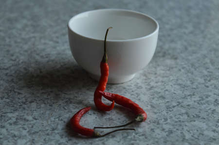Red chillies with white bowl isolated on white texture marble tableの写真素材