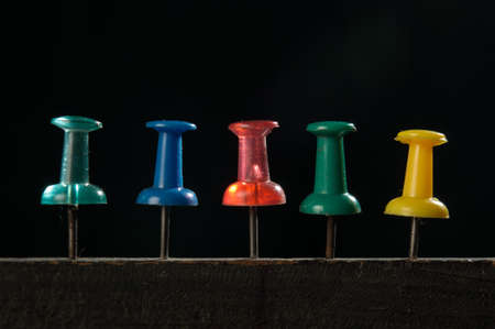 Macro photography of push pin which is pinned on wood with black background at studio
