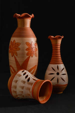 Still life with hand painted and hand made red jar isolated on the black background
