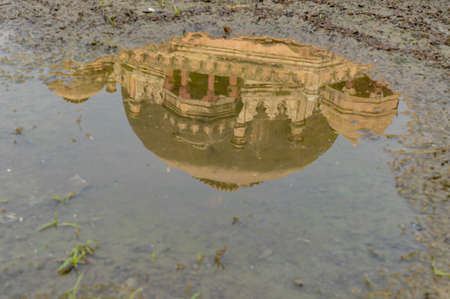 A reflection in water of tomb of sikandar lodhi monument at lodi garden or lodhi gardens in a city park from the side of the lawn at winter foggy morning.の写真素材