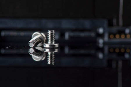 Component parts of a disassembled hard drive, close-up on a dark background.