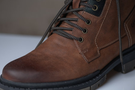 Fragment of fashionable men's brown winter boot made of genuine leather with fur.