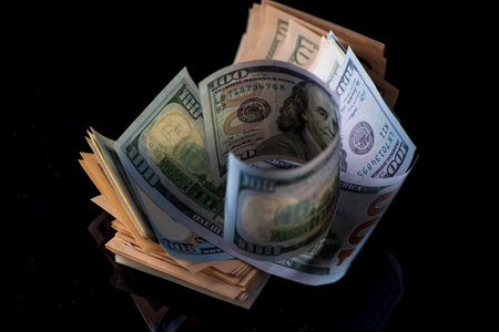 A lot of American dollars banknotes on a dark background.