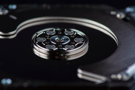 Component parts of a disassembled hard drive, close-up on a dark background.