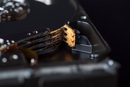 Component parts of a disassembled hard drive, close-up on a dark background.