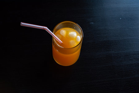 Orange juice with ice cubes on a black background. Refreshing drink.の写真素材