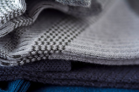 Closeup detail of a stack of knitted gray sweaters.