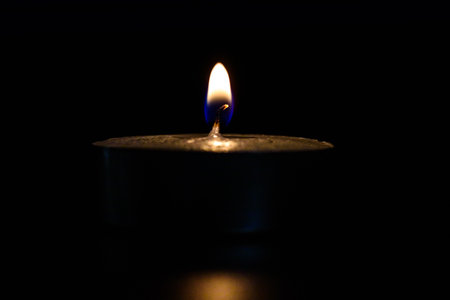 The fire of a dying candle on a dark background.