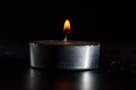 The fire of a dying candle on a dark background.の写真素材